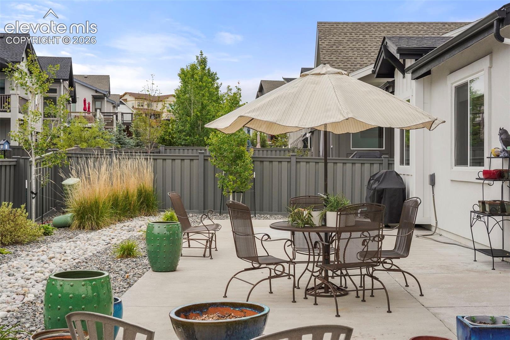 Concrete patio with white exterior siding and multiple windows