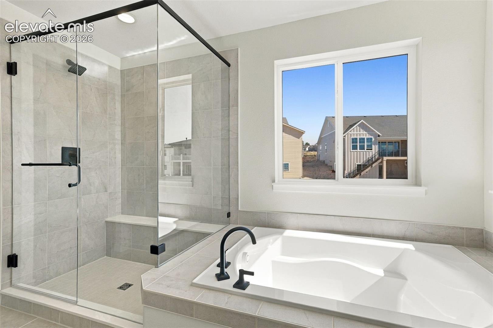 Spacious bathroom featuring a built-in soaking tub with matte black fixtures