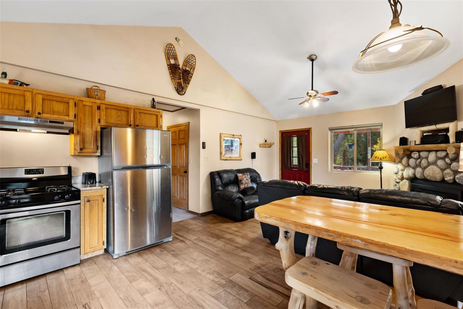 Vaulted ceiling, wood-finish flooring, stainless steel appliances, stone-clad fireplace, and recessed lighting