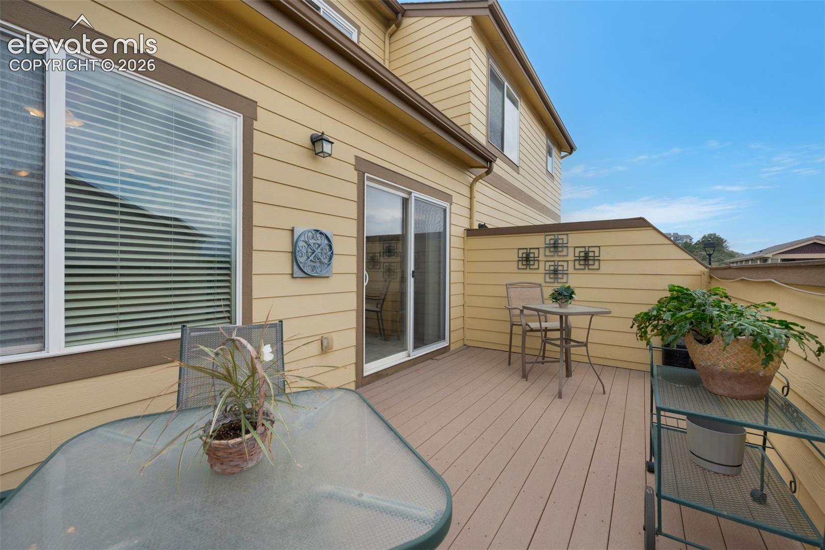 Exterior deck featuring composite wood-finish flooring, a sliding glass door, an exterior light fixture, and horizontal siding