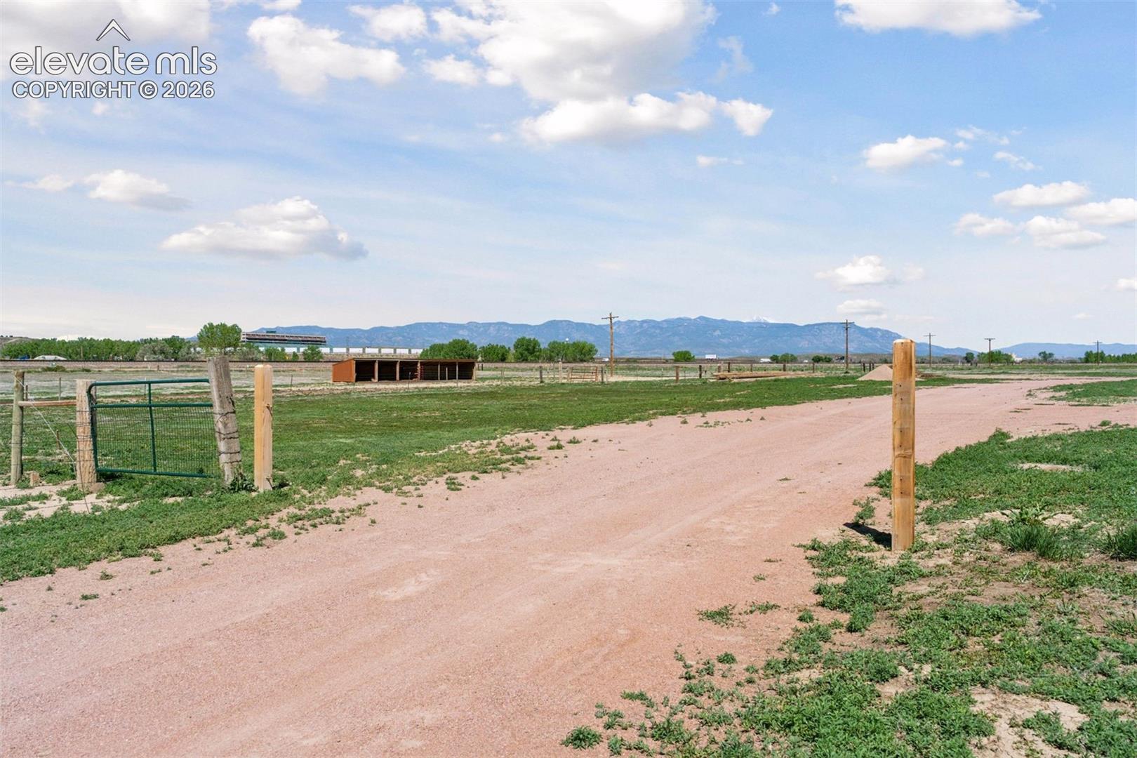 Mountain-view outlook near the shared access road, with distant views toward Pikes Peak International Speedway across I-25 and the surrounding open landscape