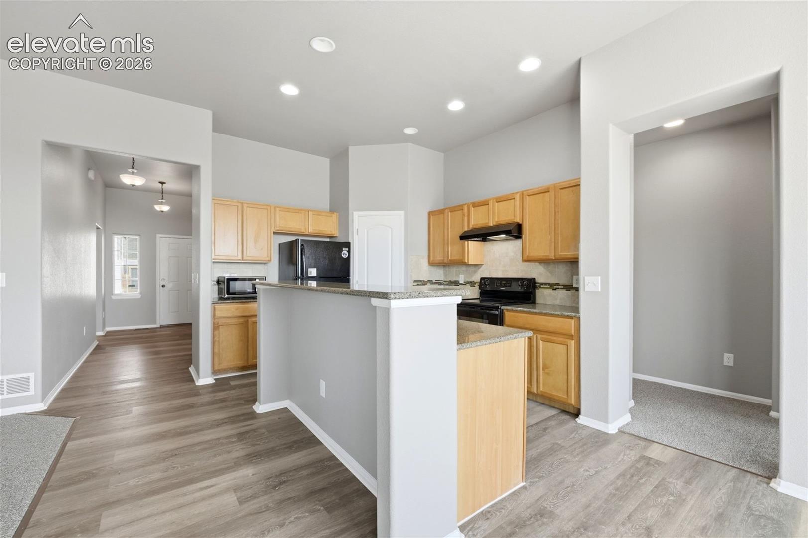 Kitchen with wood-finish cabinetry, built-in appliances, a tiled backsplash, and recessed lighting