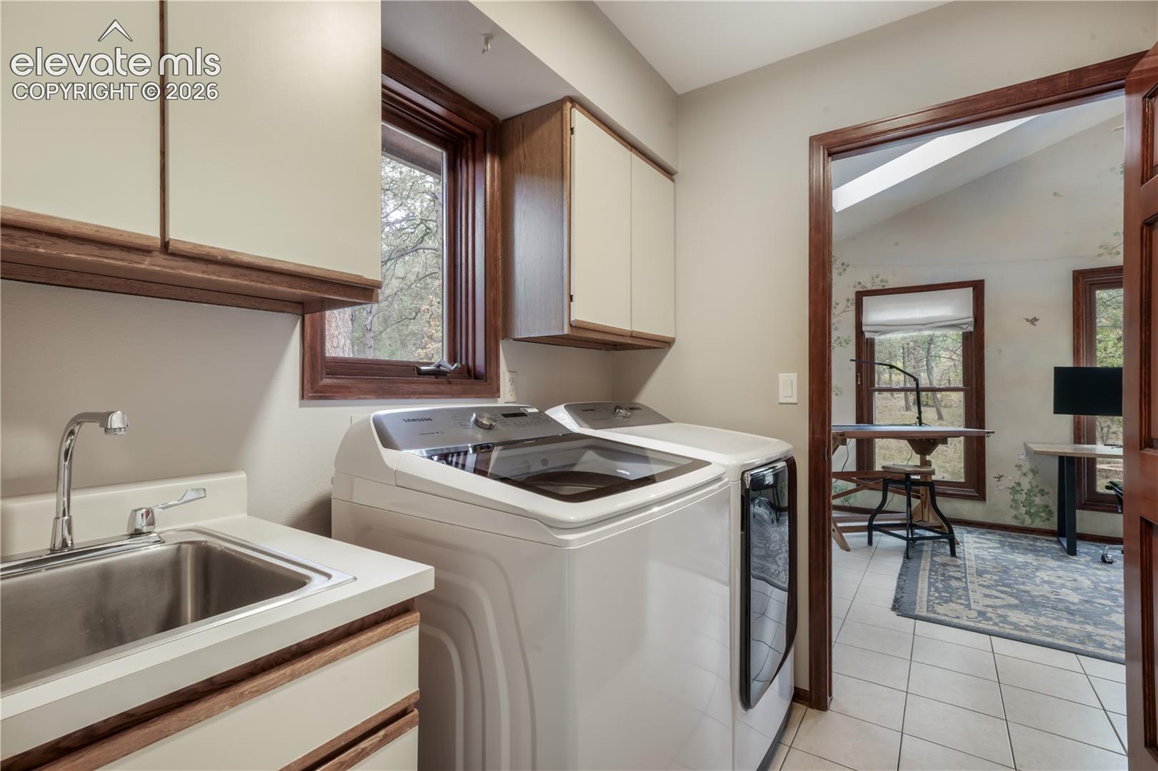 Main level laundry room with tons of storage, sink and a window