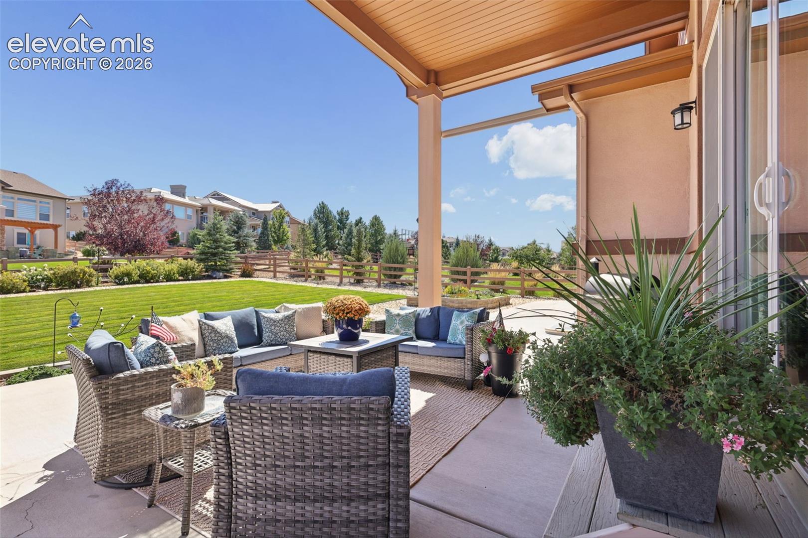 Covered patio with an expansive manicured lawn and a privacy fence