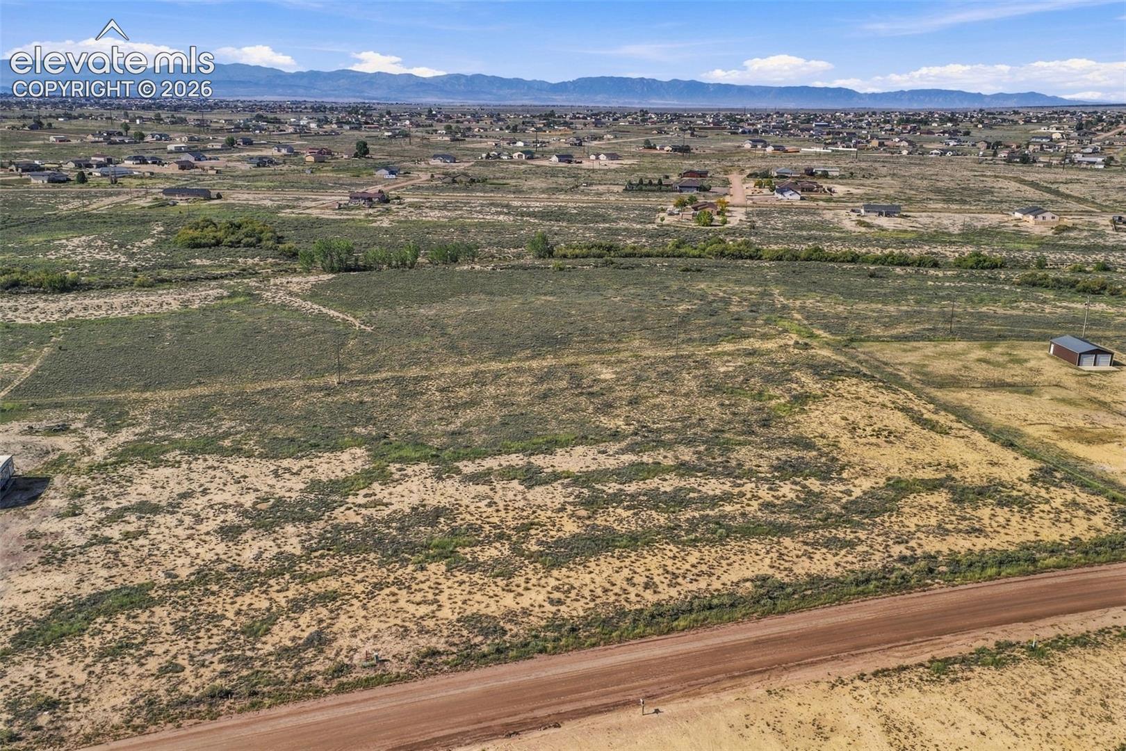 Expansive parcel of land featuring native vegetation, a detached storage structure, and mountain range backdrop