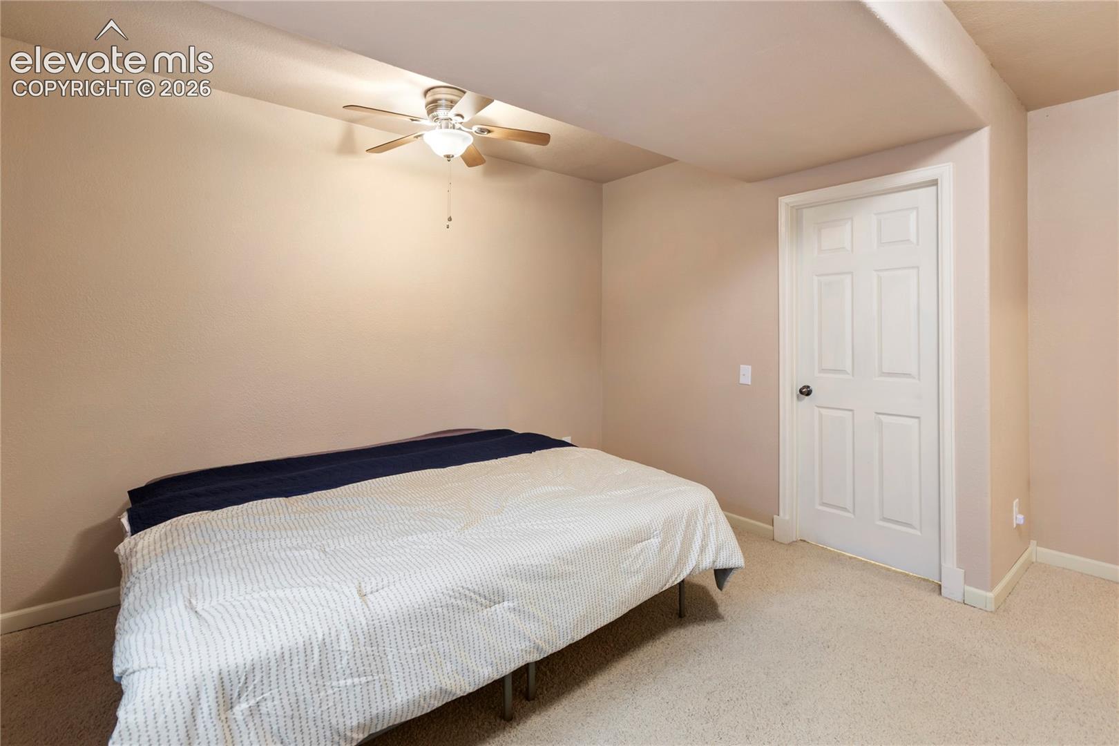Carpeted flooring, recessed ceiling, ceiling fan with light fixture, white paneled door, and neutral wall tones