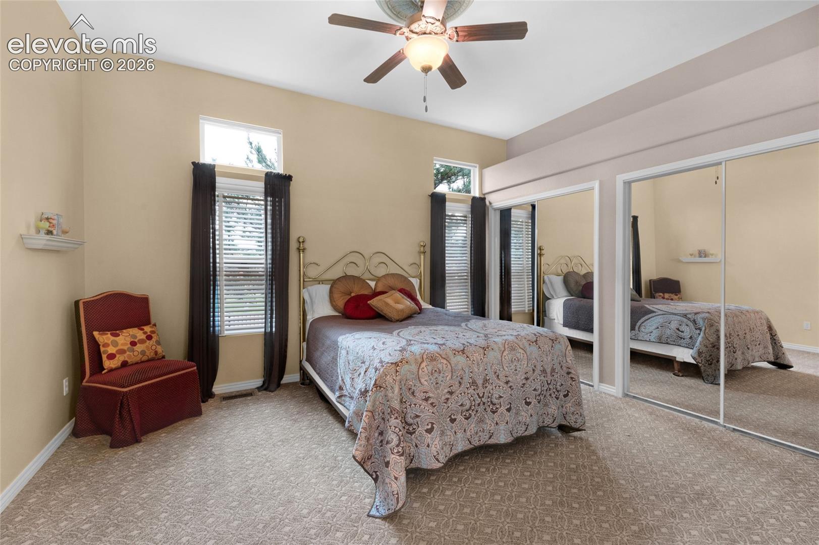 High ceilings, large windows with natural lighting, wall-to-wall carpeting, and dual sliding mirrored closet doors with a central ceiling fan