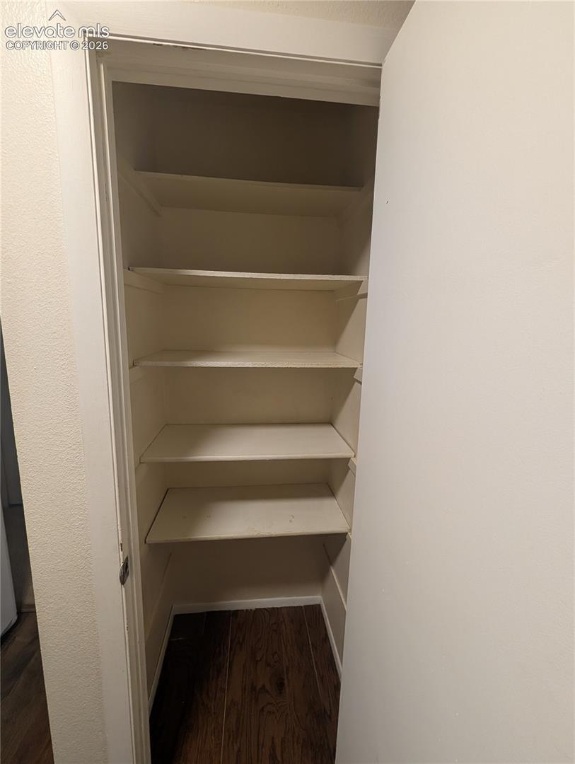 Built-in shelving with multiple levels, wood-finish flooring, and a white door