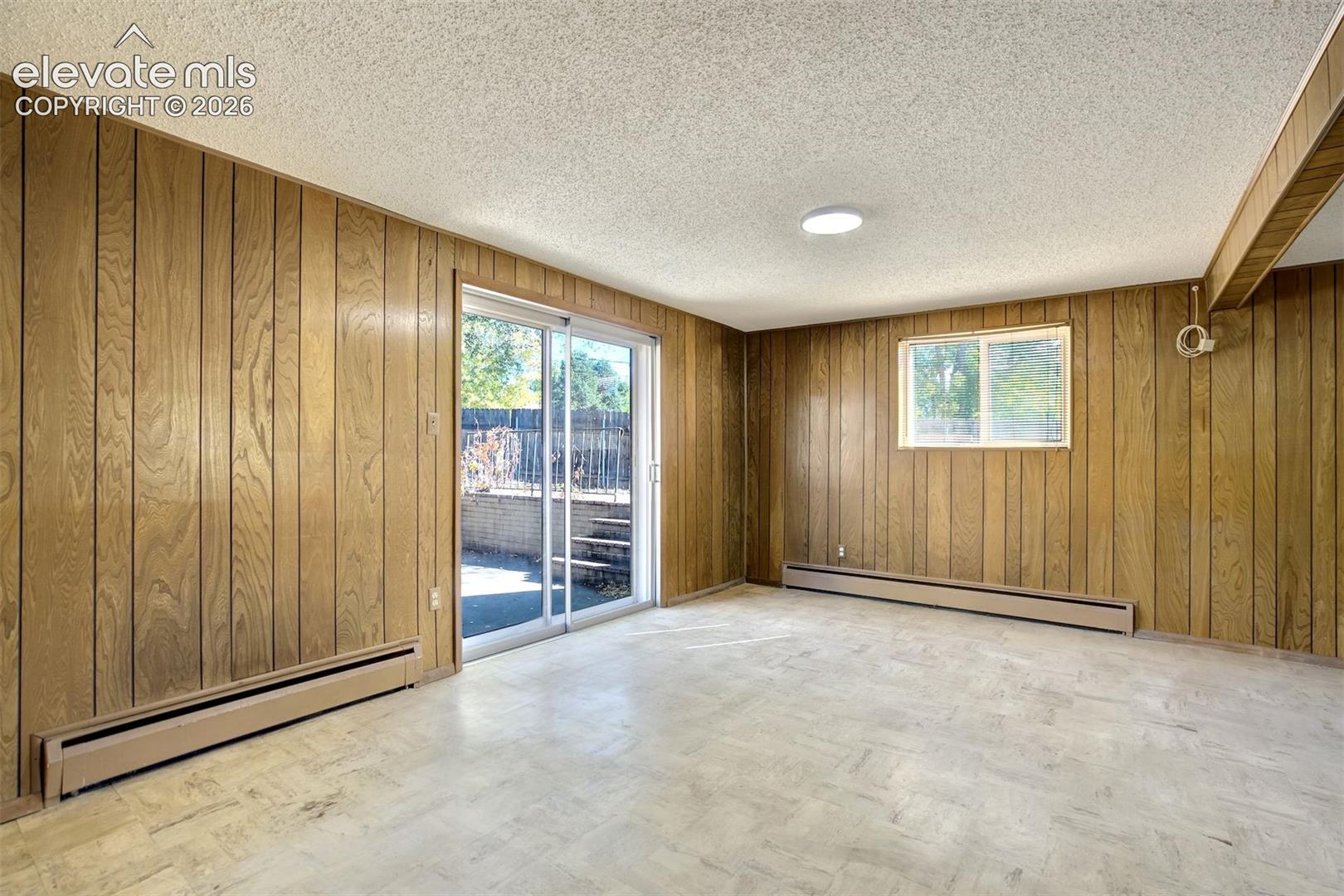 Interior space featuring wood paneling, sliding glass door, single-pane window, and tile flooring