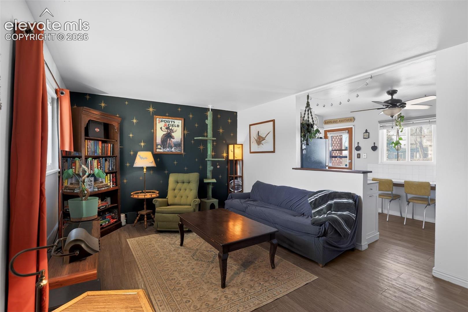 Open concept living space with wood-finish flooring, a built-in bookshelf, and a partial wall separating living and dining areas