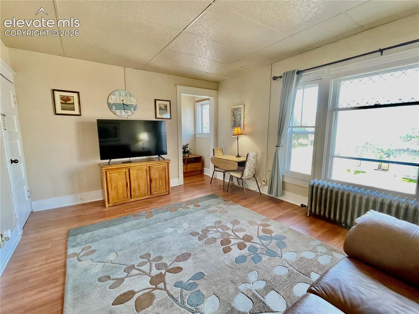Wood-finish flooring throughout, light-toned wall paint, white trim, and ample natural light from multiple windows
