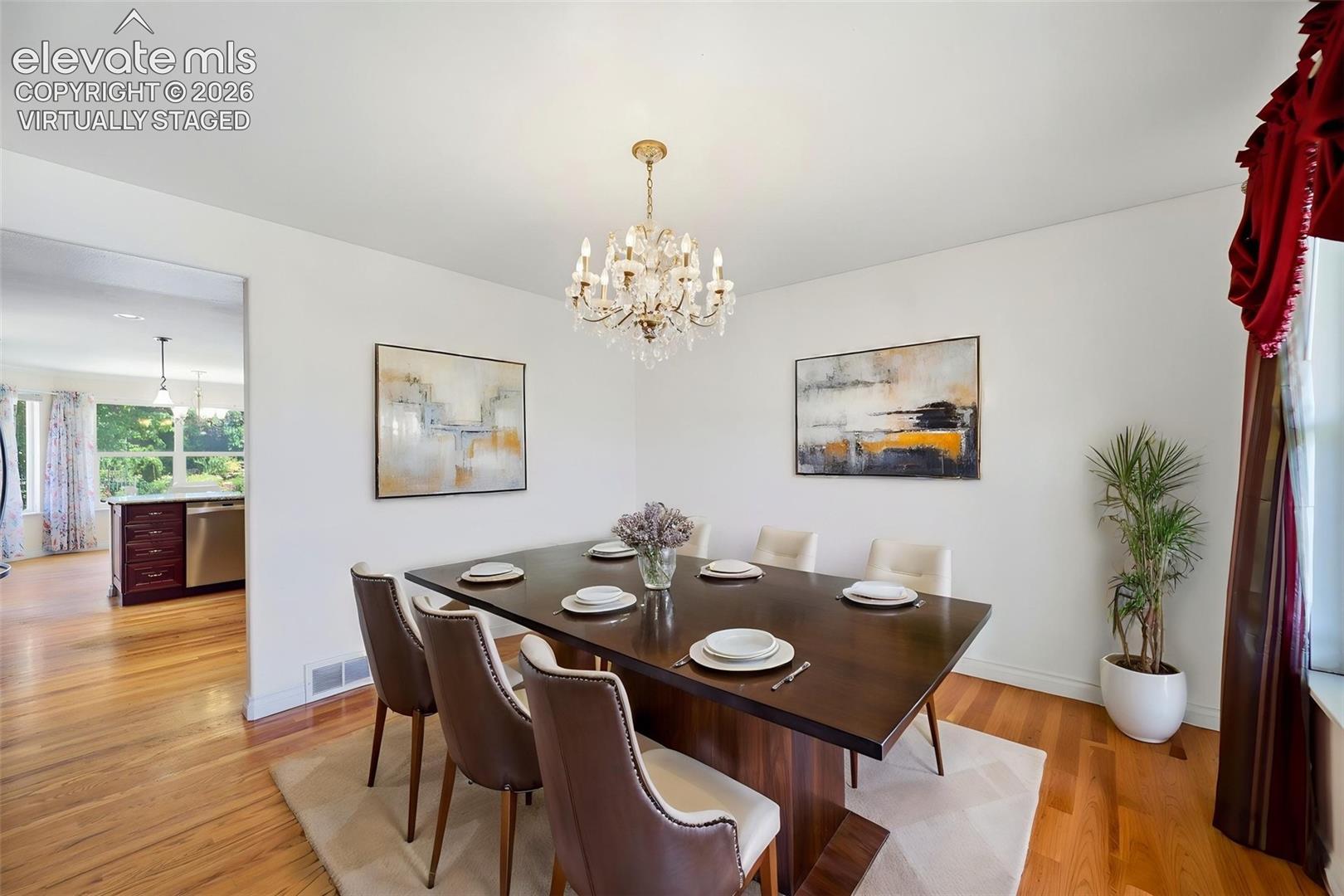 virtually staged  formal dining space featuring a chandelier, hardwood flooring, and a wide entryway