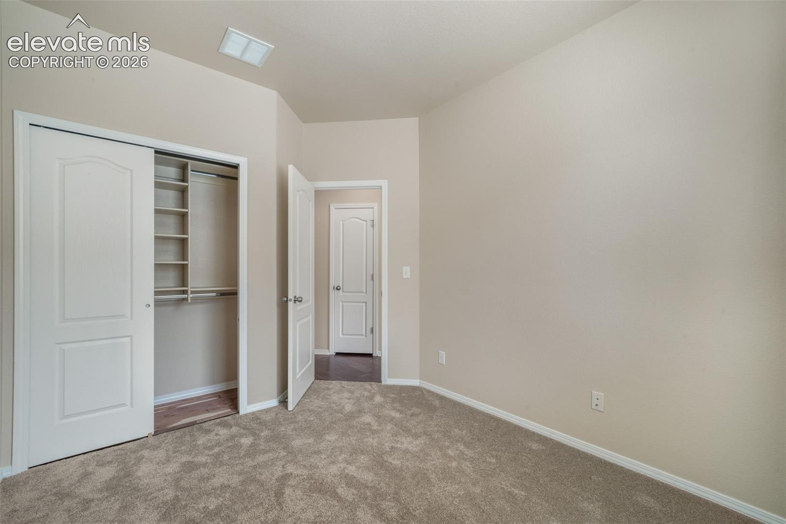 Wall-to-wall carpeting, light-toned wall finishes, vaulted ceiling, built-in closet shelving, and a two-panel interior door