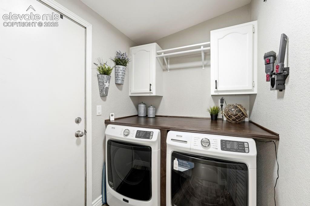 Dedicated laundry area featuring white cabinetry, a dark wood-finish countertop, and a clothes hanging rod