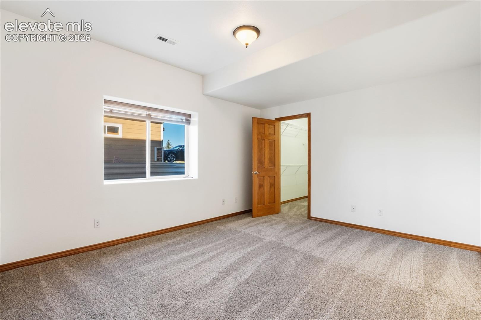 Neutral-toned carpeting, wood-finish interior door, recessed ceiling lighting, and built-in closet shelving