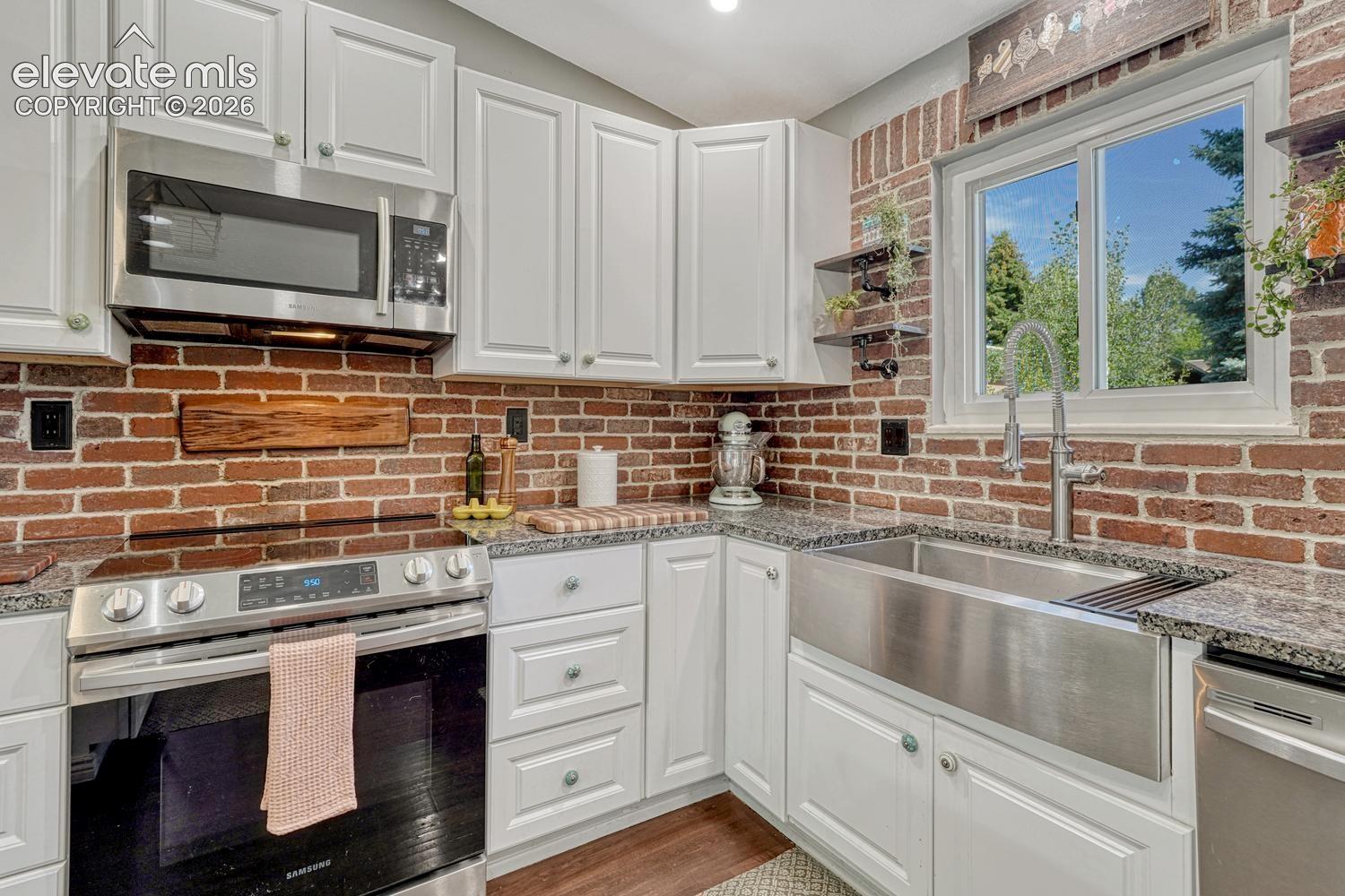 Stainless steel appliances include a smooth top range oven, built-in microwave, farm house sink, dishwasher, and French door refrigerator.