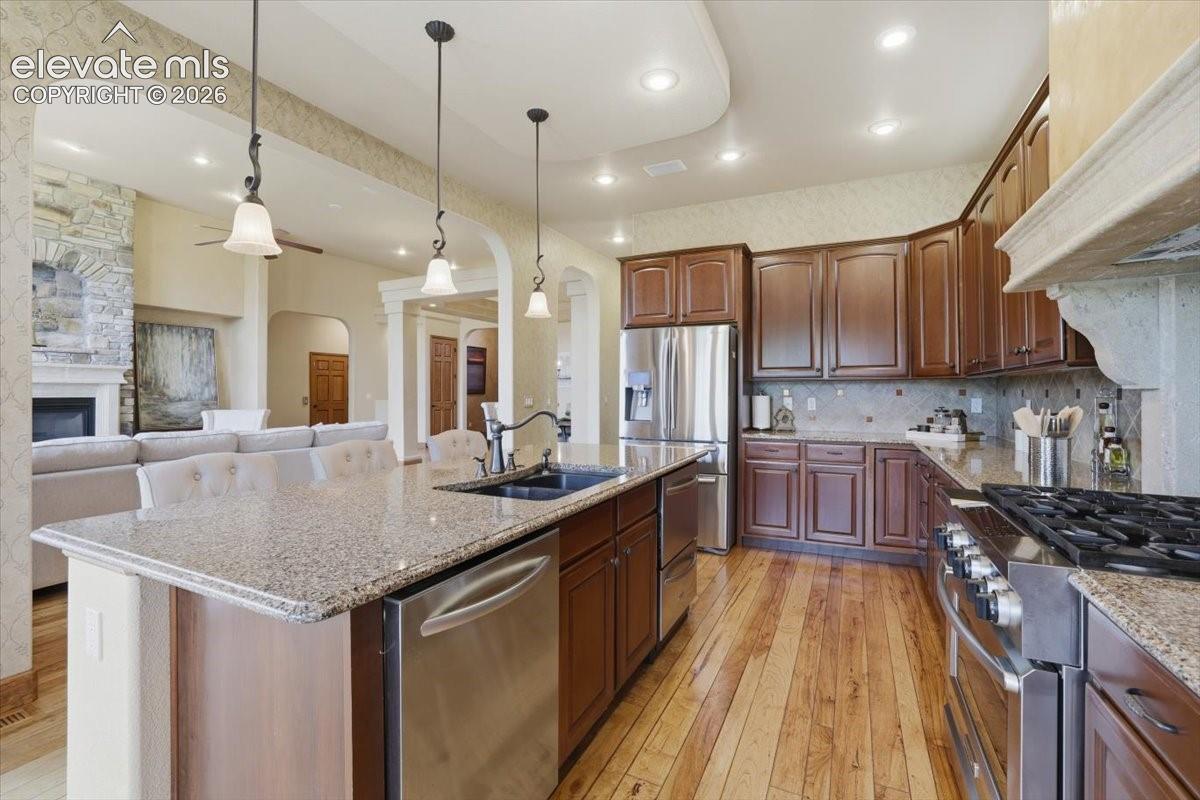 Gourmet Kitchen with Wood Flooring, Island, Granite Countertops, Deco Tile Backsplash, Hood Vent wrapped in Italian Plaster! Stainless Steel Appliances include a Dishwasher, Two Dishwasher Drawers, French Door Fridge, Warming Drawer, Built-in Oven, Built-in Microwave, and a 6-burner Gas Range atop a Second Oven.