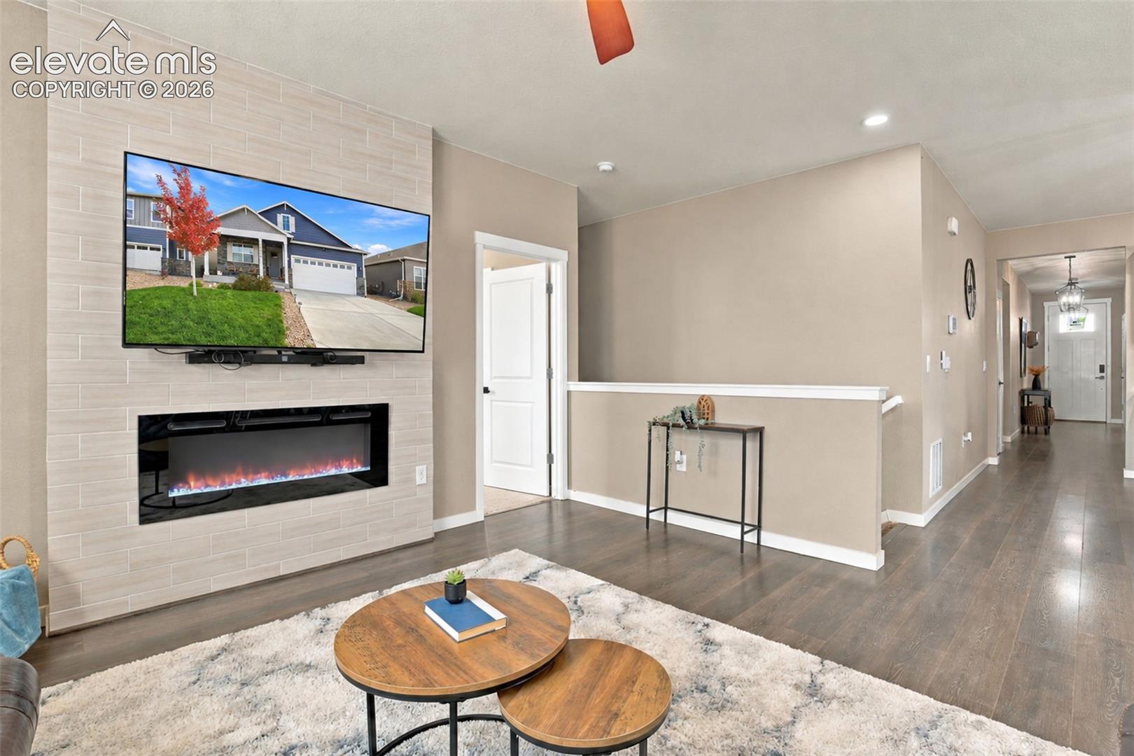 Floor-to-ceiling fireplace surround with linear electric firebox, wood-finish flooring, and crisp white millwork accents