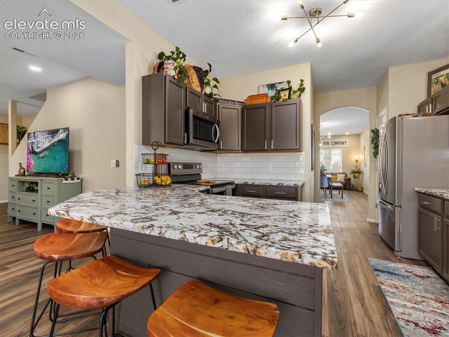 Kitchen featuring a patterned countertop, stainless steel appliances, dark cabinetry, subway tile backsplash, and LVP flooring