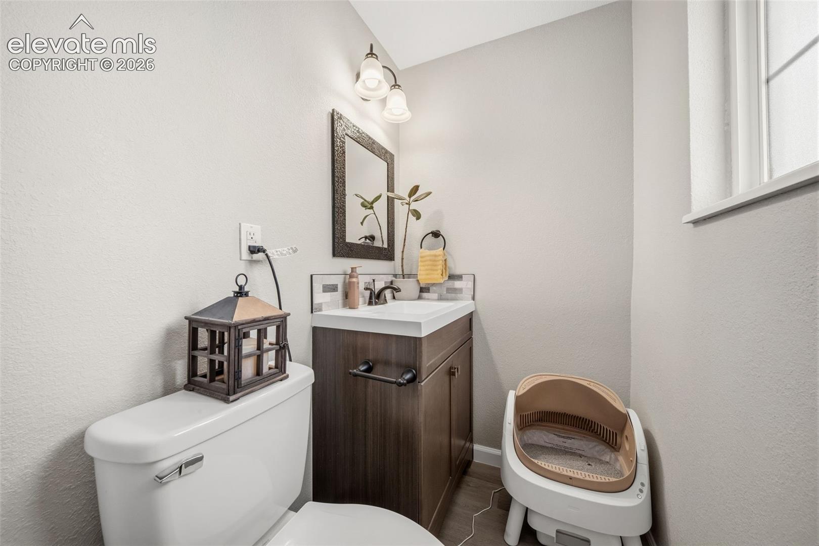 Vanity with dark wood-finish cabinetry, white countertop, and dark-framed mirror