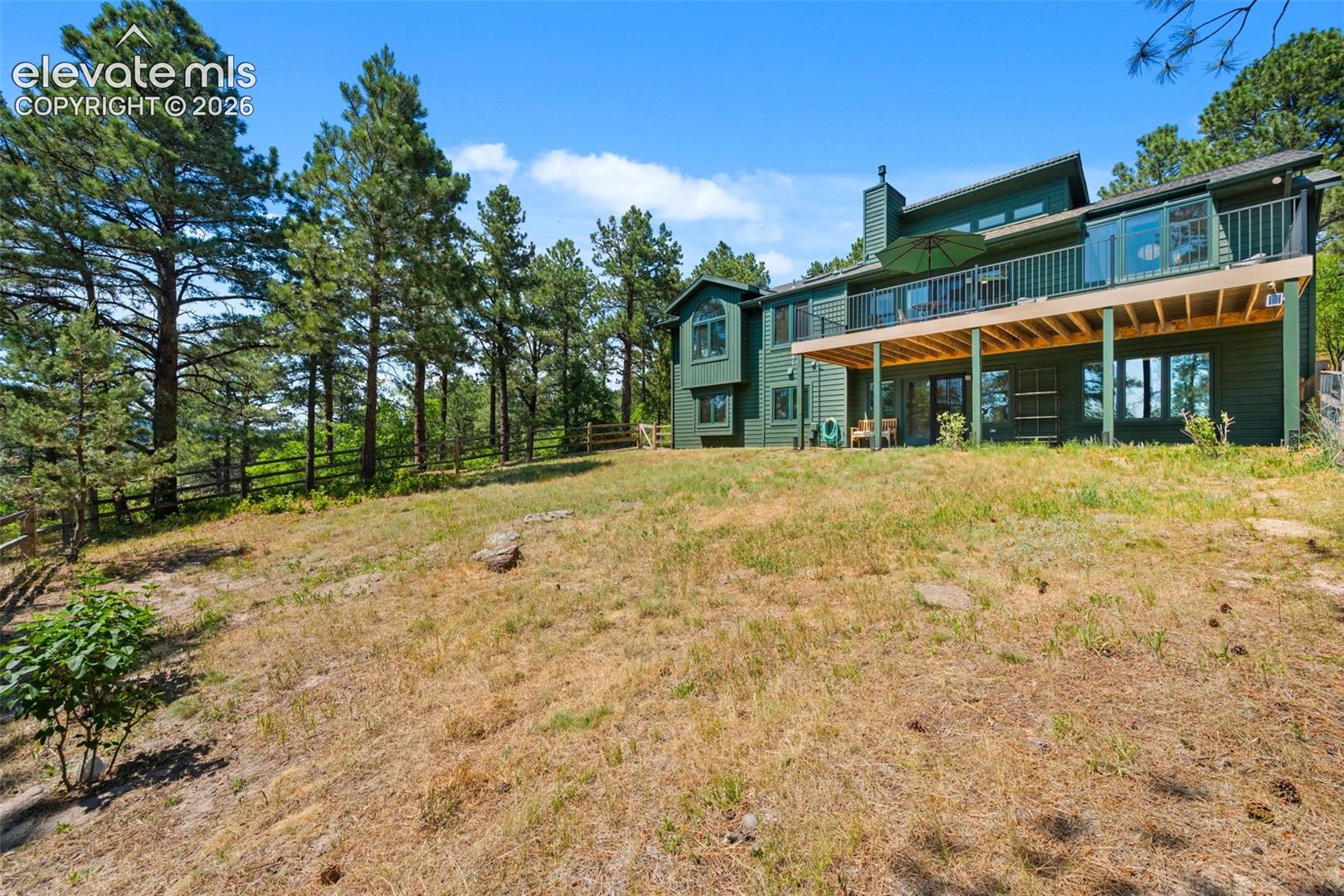 Contemporary multi-level residence featuring a large elevated deck with glass panel railings