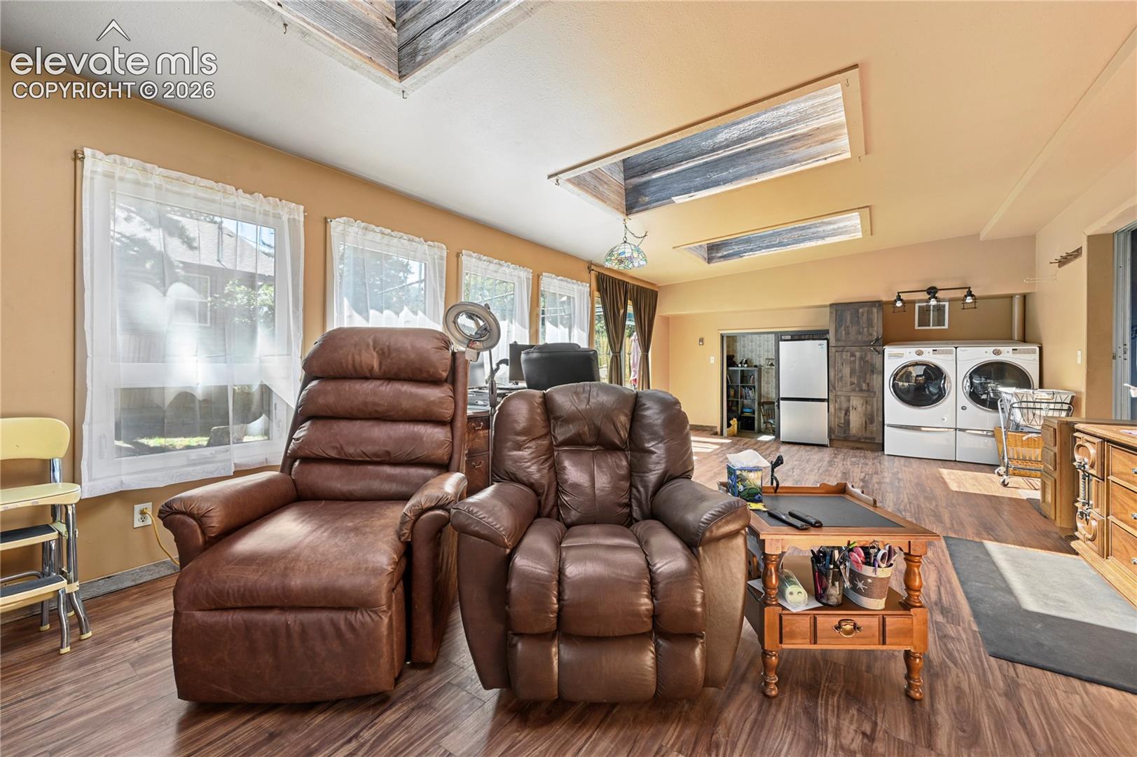 Sloped ceiling with recessed skylights, wood-finish flooring, multiple windows, and a dedicated laundry area with appliances