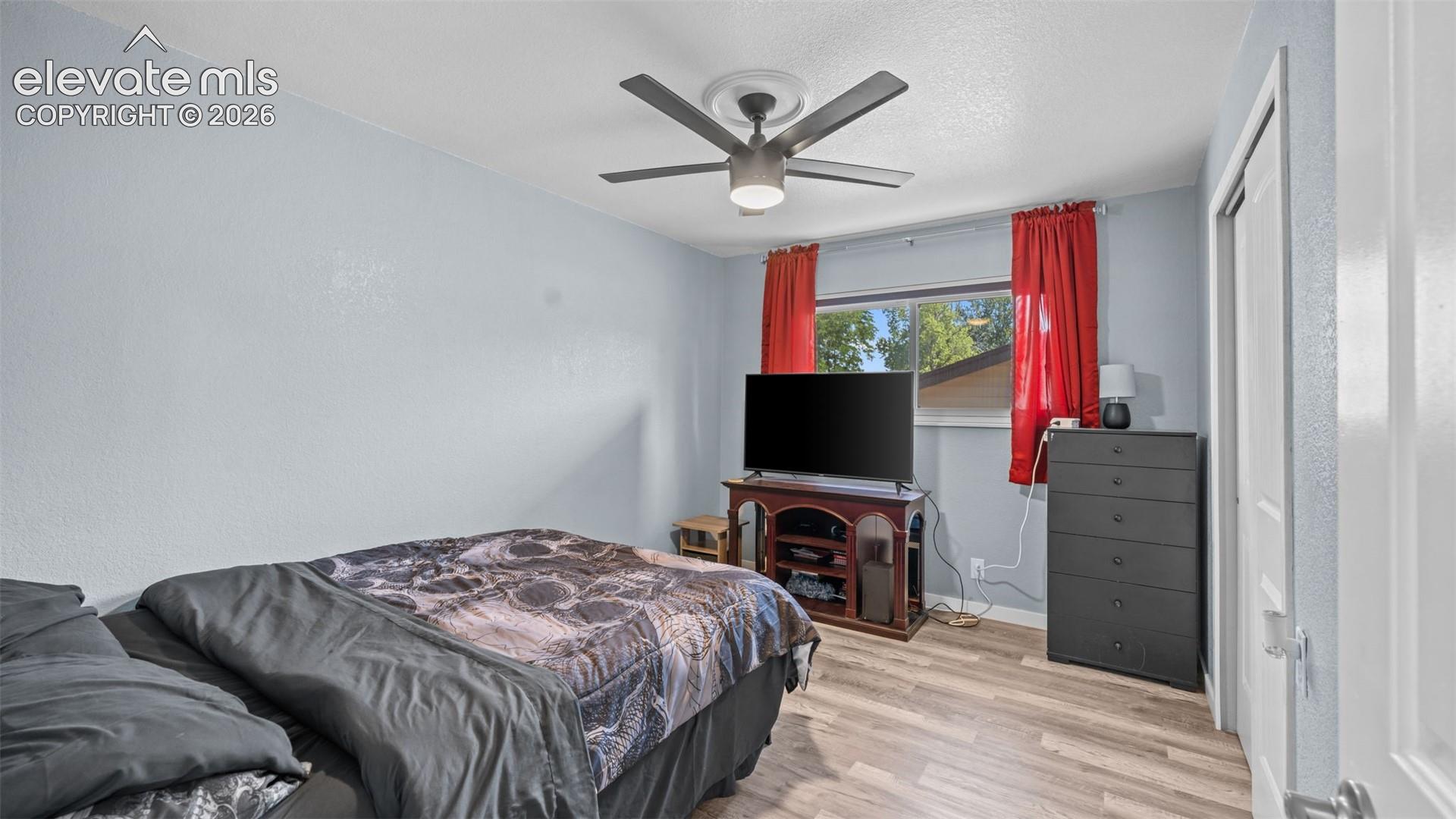 Bedroom featuring wood-finish flooring, a ceiling fan with integrated lighting, and a window with natural light
