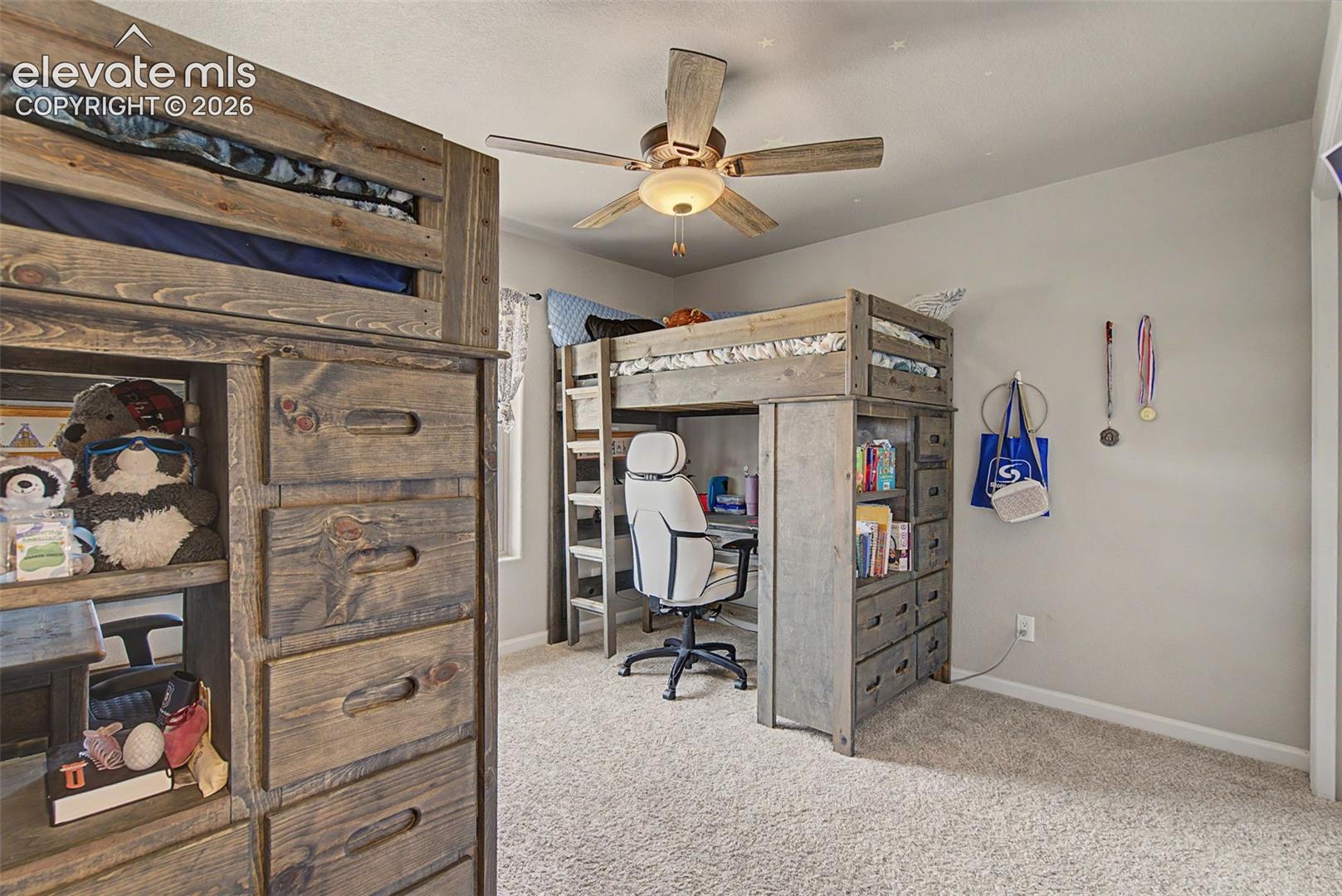 Carpeted room featuring a ceiling fan with integrated lighting, two built-in loft beds with integrated storage, and a desk area