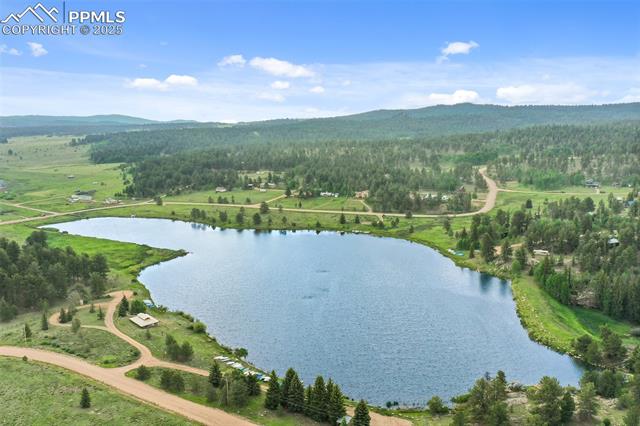 Drone / aerial view of a heavily wooded area and a water and mountain view