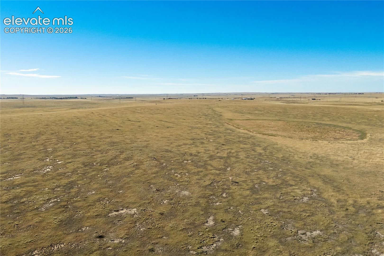 Expansive parcel of open land featuring native grasses and level topography