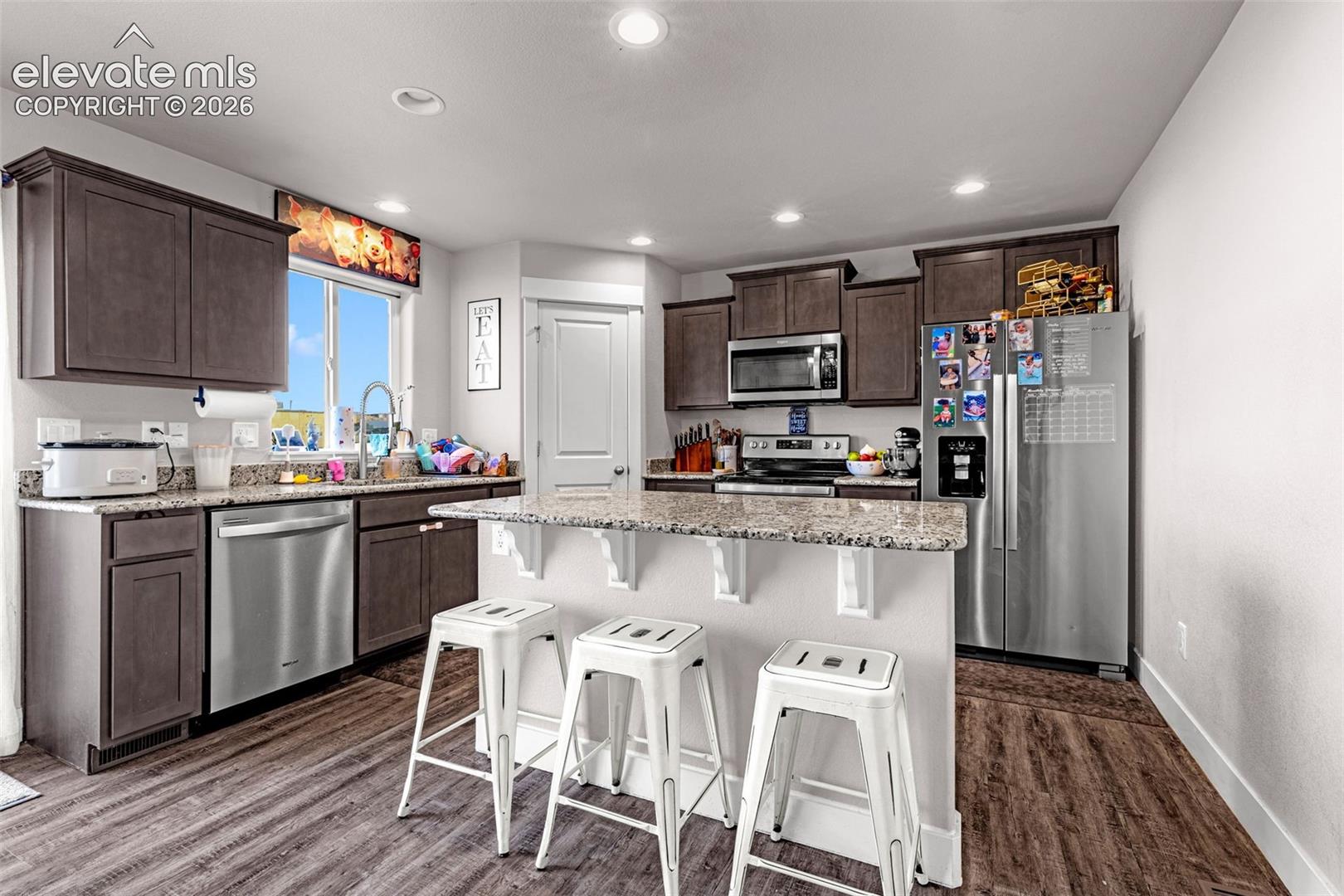 Modern kitchen featuring wood-finish flooring, dark wood cabinetry, and speckled countertops