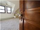 Solid wood paneled door with antique-style crystal knob, sloped ceiling, and double-pane windows