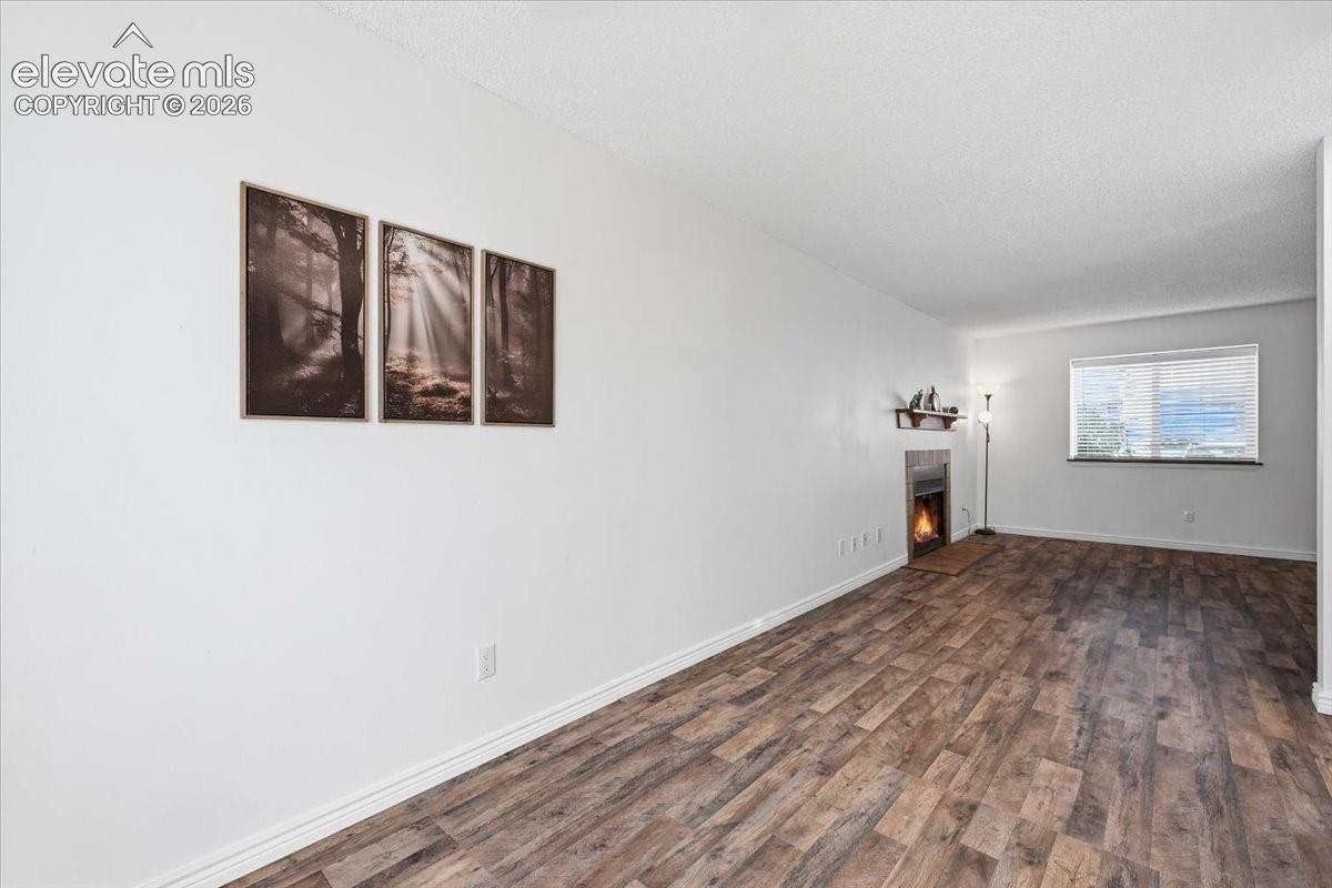 Living area featuring wood-finish flooring, a built-in fireplace, a window with horizontal blinds, and a neutral color palette