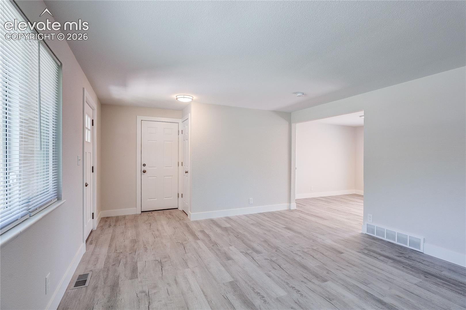 Neutral-toned interior featuring wood-finish flooring, white panel doors, and a flush-mount ceiling light fixture