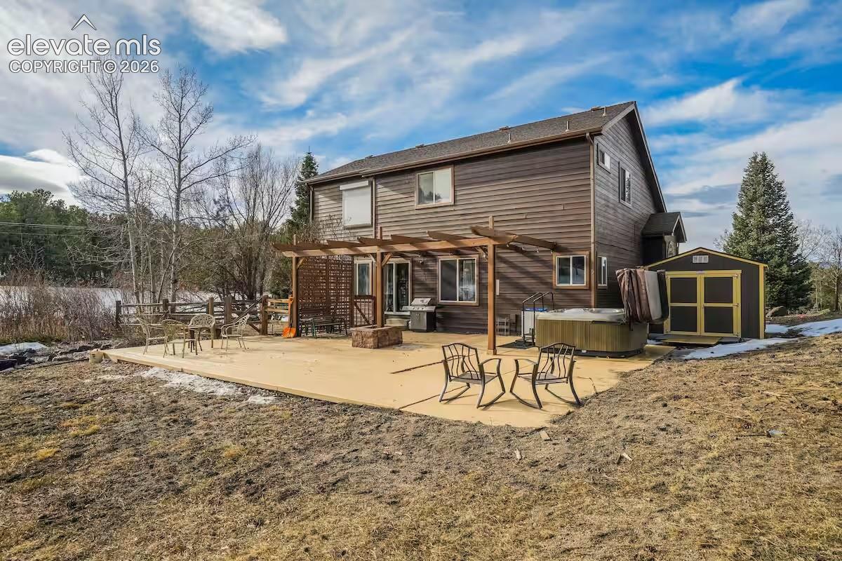 Spacious outdoor patio area featuring a hot tub, a pergola structure, and a storage shed
