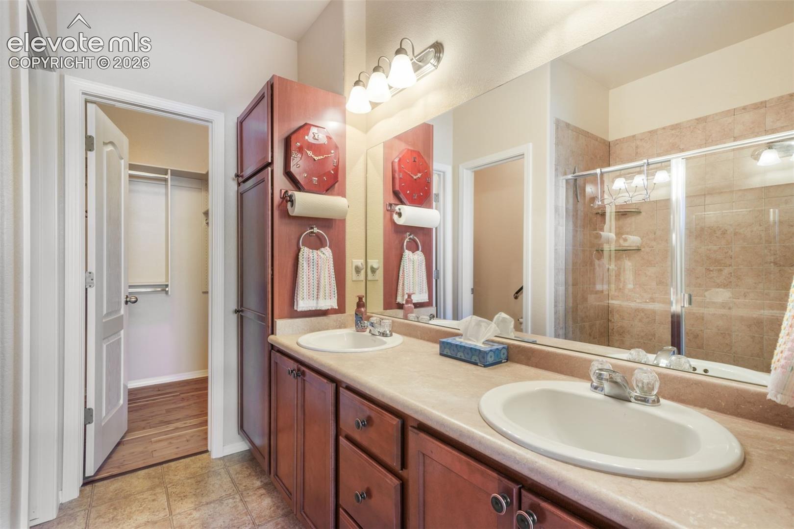 Dual vanity with integrated sinks, wood-finish cabinetry, and a full-width mirror