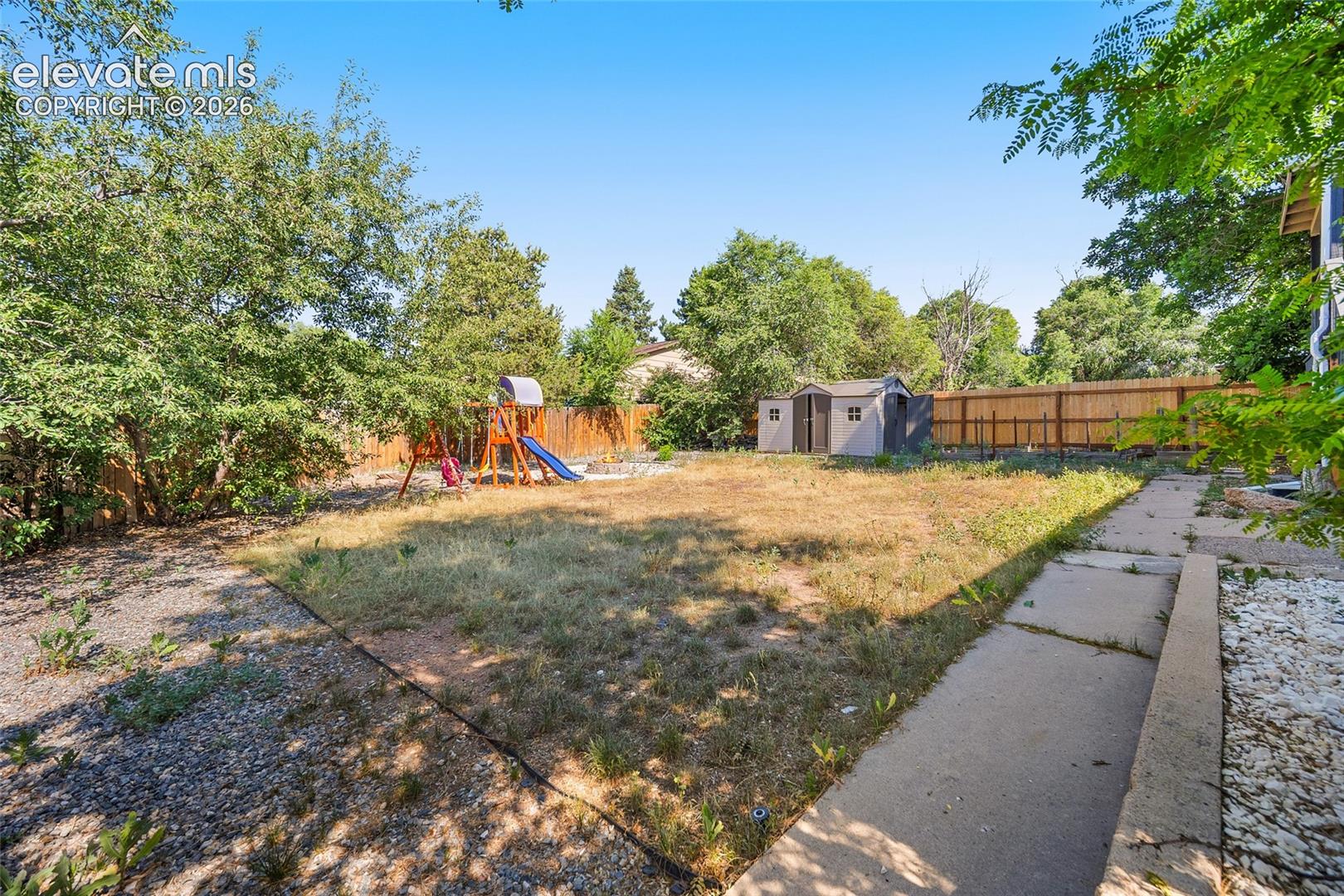 Private backyard with mature trees and open lawn.