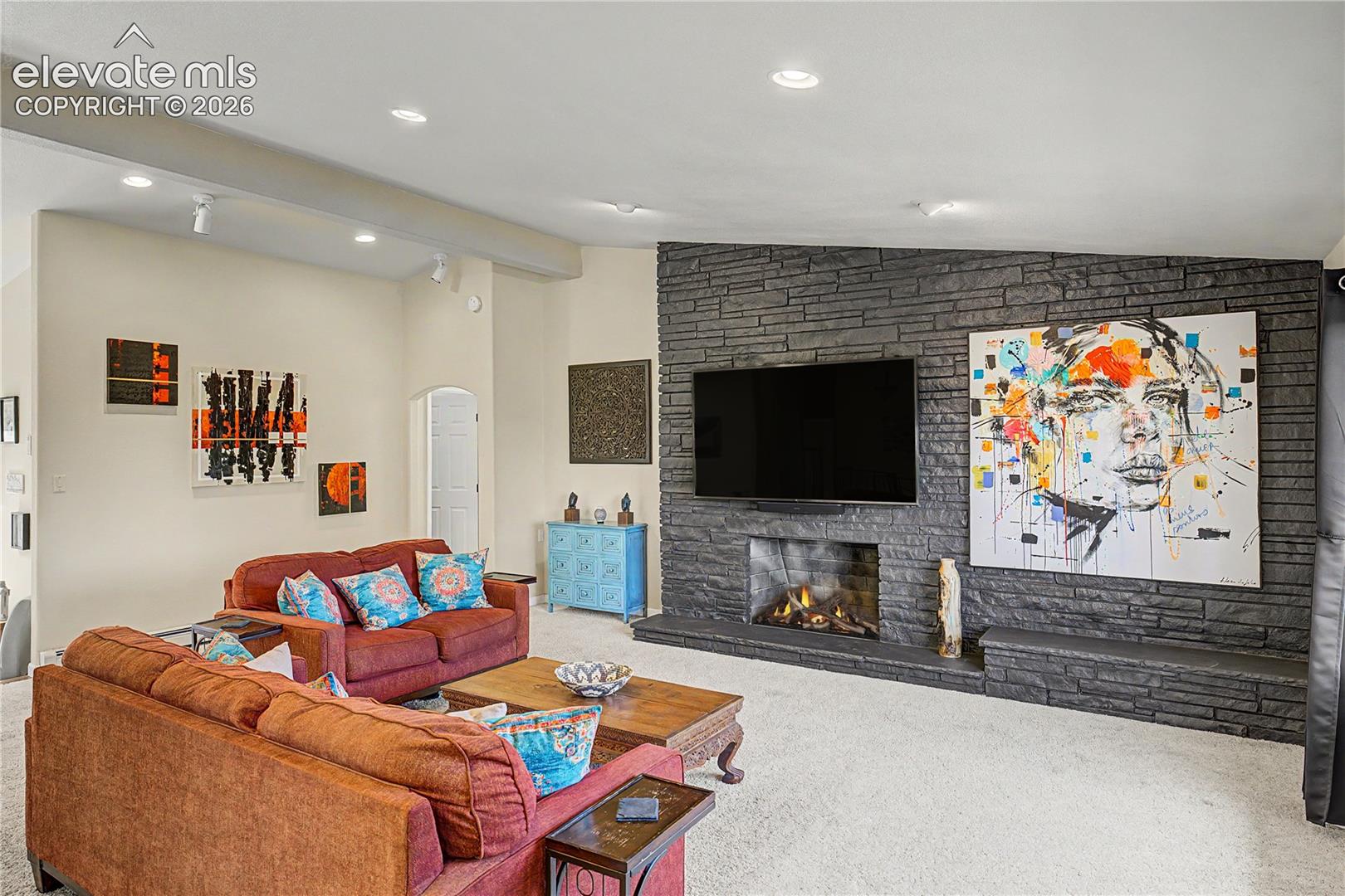 The living room's showstopper comes into view: a dramatic, floor-to-ceiling stacked-stone fireplace rising beneath vaulted, skylit ceilings, the kind of statement feature that anchors a home for decades.