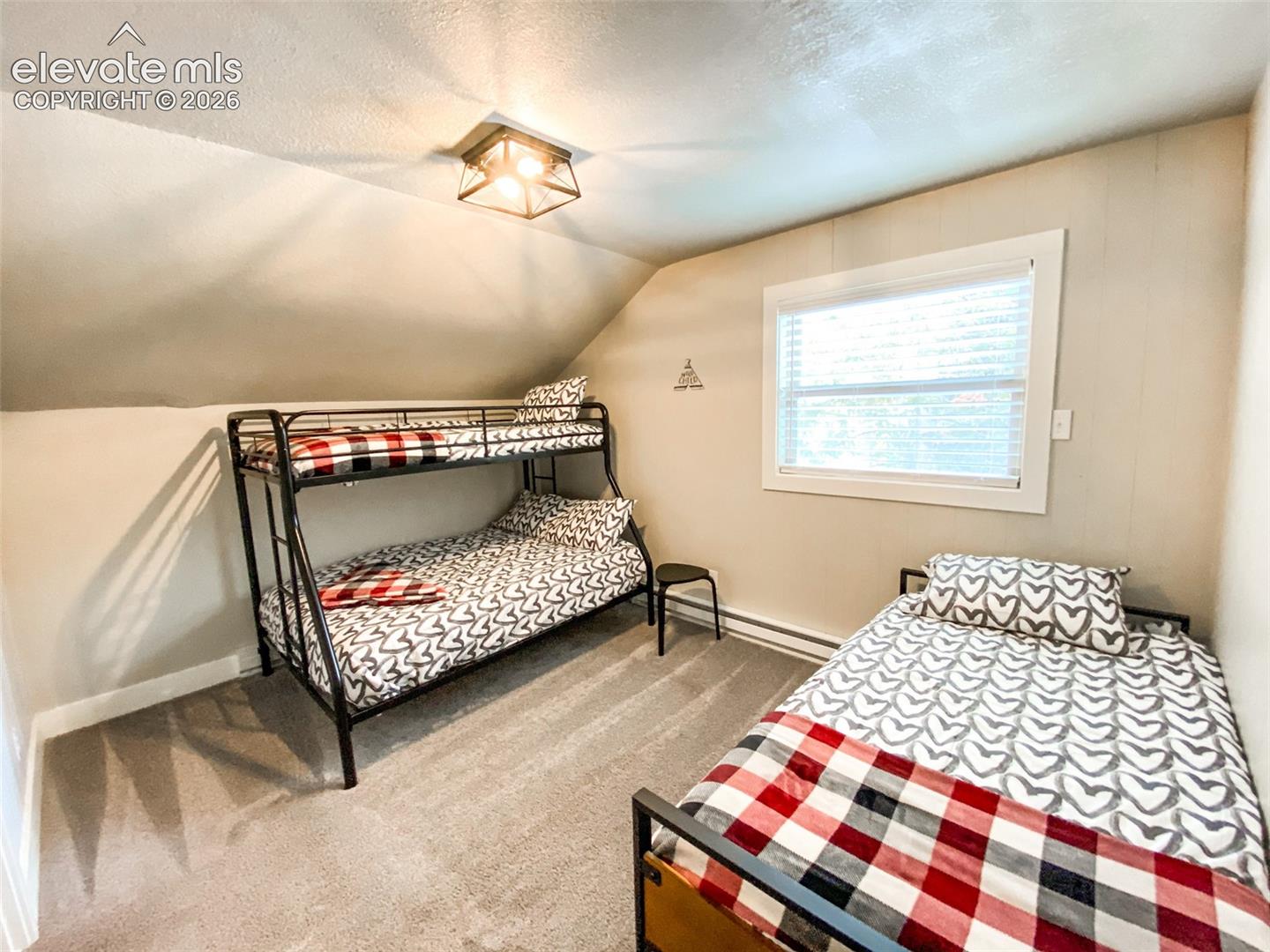 Bedroom featuring sloped ceilings, recessed window with blinds, and light gray wall paneling