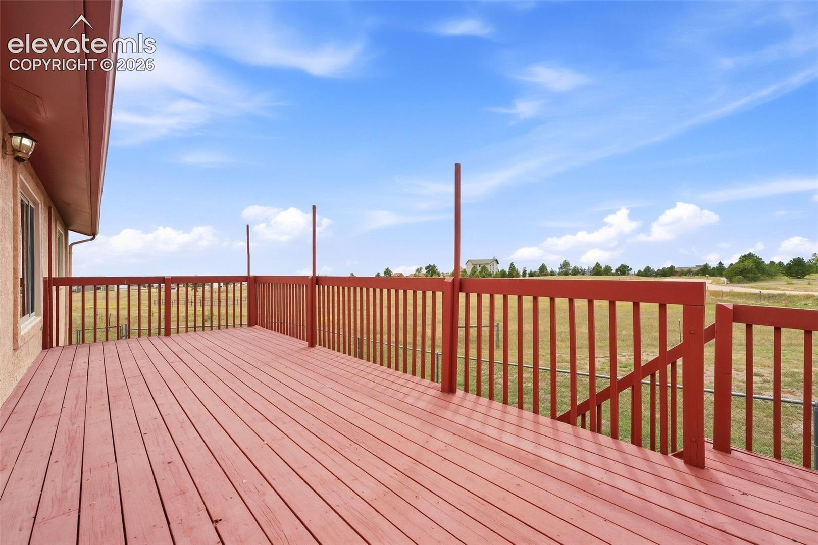 Expansive wood deck with a red finish, full perimeter railing, and integrated staircase