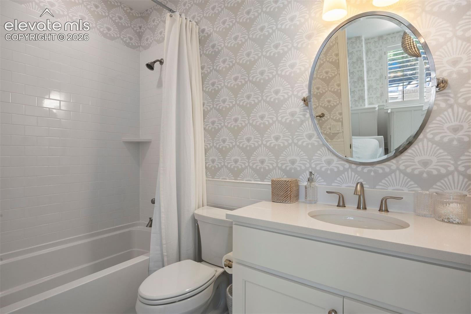 Bathroom featuring a white subway-tiled tub and shower combination with an integrated corner shelf