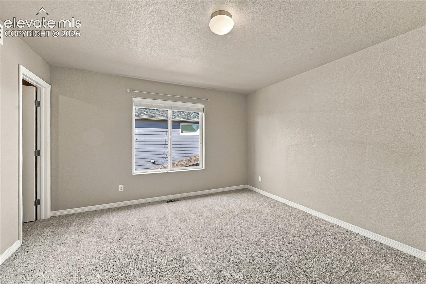 Neutral wall-toned room with plush carpeting, smooth-finish ceilings, an energy-efficient window, and a ceiling-mounted flush light fixture