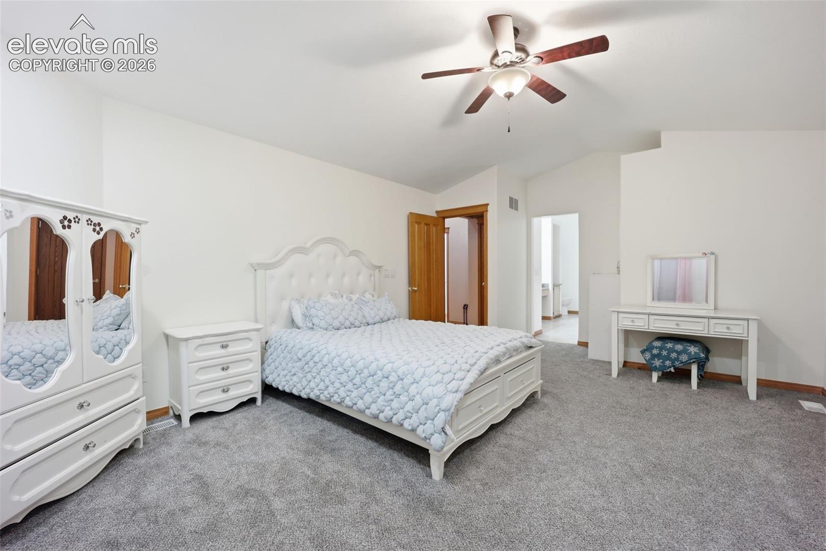 Vaulted ceilings with a ceiling fan, light gray carpet, and wood-finish doors
