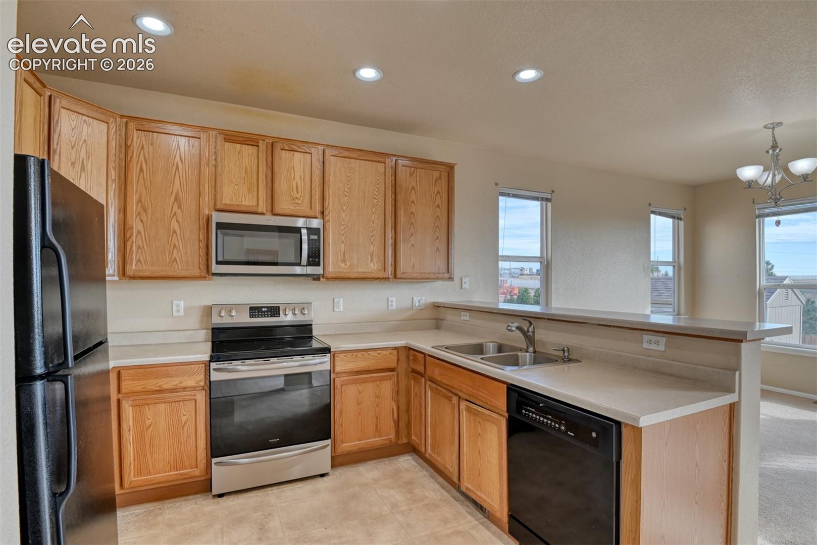 Kitchen featuring natural wood cabinetry, solid surface countertops, recessed lighting, and stainless steel appliances