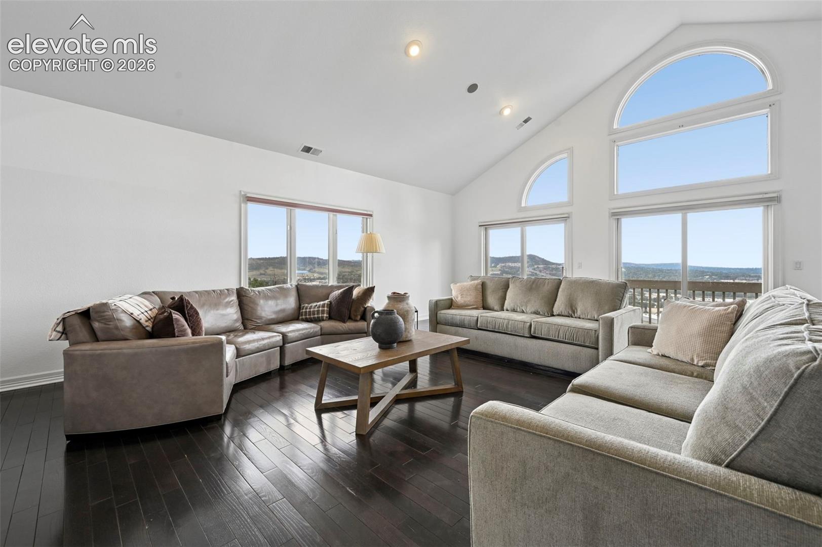 Vaulted ceiling with multiple recessed lights and large arch-top windows