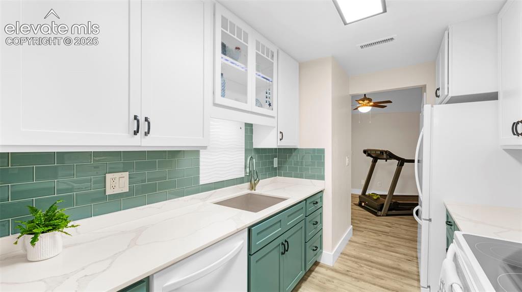 Contemporary kitchen featuring white upper cabinetry, teal lower cabinetry, and dark hardware