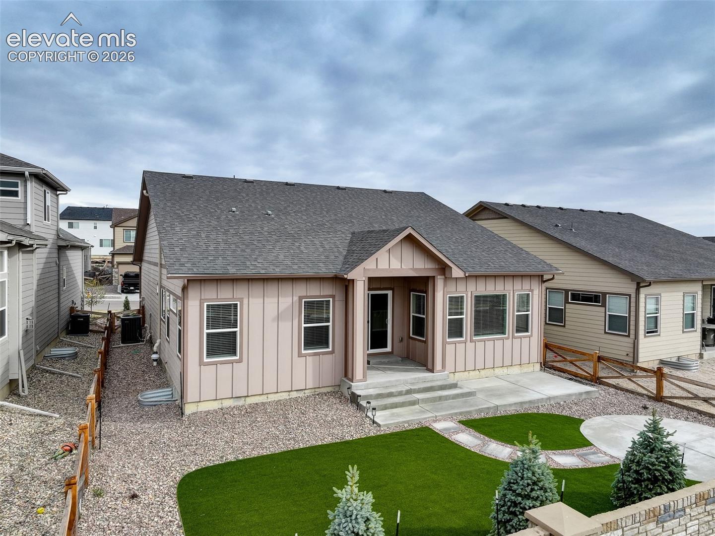 Backyard featuring artificial turf, decorative gravel, and a concrete patio