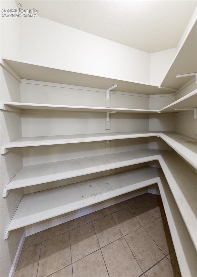Storage area featuring multi-level wrap-around shelving and ceramic tile flooring