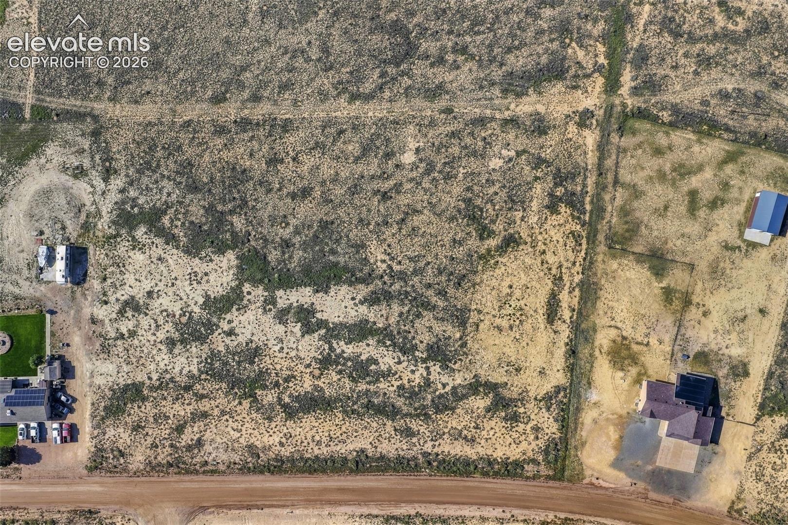 Expansive parcel of land featuring native vegetation, natural terrain, and direct frontage to an unpaved road