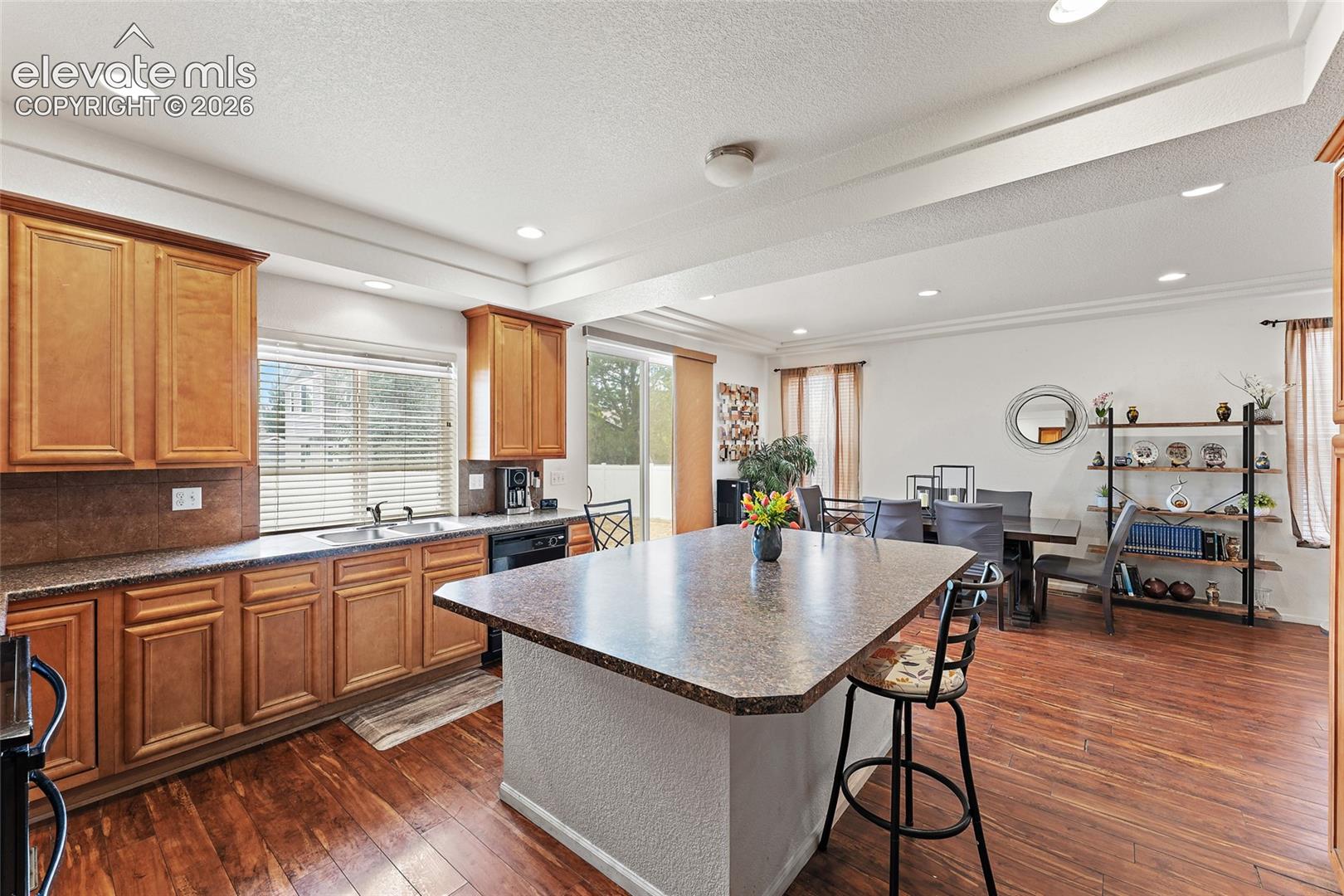 Kitchen featuring wood-finish cabinetry, central island with extended countertop, recessed lighting, and wood-finish flooring